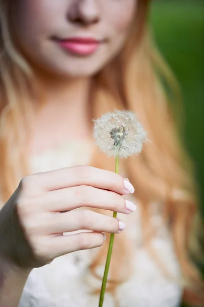 Fille soufflant sur un pissenlit, doucement. le sourire le visage — Photo