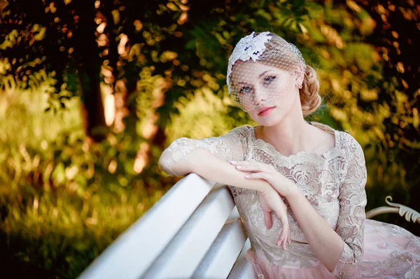 Schöne Blondine mit Frisur und Schleier auf Bank sitzend, romantisches Aussehen — Stockfoto