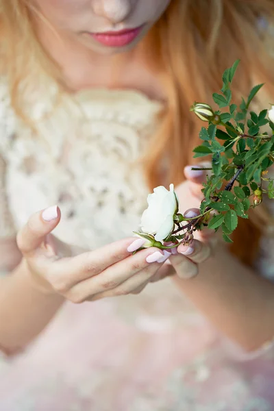 Mädchen in einem hellen Kleid, das eine Rose auf einem Ast hält. Zärtlichkeit — Stockfoto