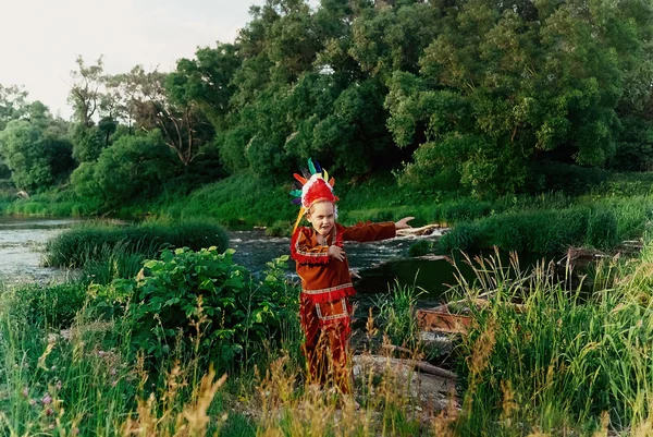 Niño en traje rojo indio de pie junto al río con el umbral y alegremente agitando sus brazos —  Fotos de Stock