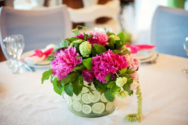 Украшение свадебного стола, прозрачная ваза с нарезанными цитрусовыми, розовые пионы на белой скатерти . — стоковое фото