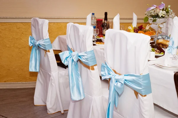 Bruiloft zaal decoratie. Stoelen in een hoes met blauwe linten — Stockfoto