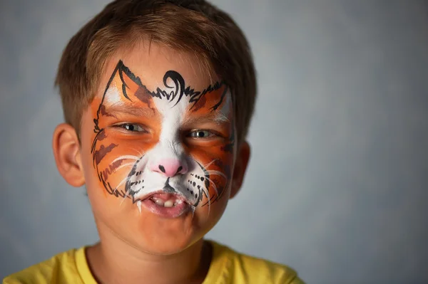 Anos de idade menino com olhos azuis pintura facial de um gato ou tigre. Laranja . — Fotografia de Stock