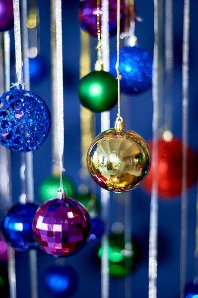 Guirnalda de Año Nuevo de bolas y lluvia contra la pared azul. Colores festivos brillantes.Celebrando el nuevo año. — Foto de Stock