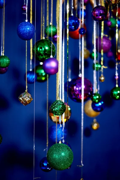 Guirnalda de Año Nuevo de bolas y lluvia contra la pared azul. Colores festivos brillantes.Celebrando el nuevo año. — Foto de Stock