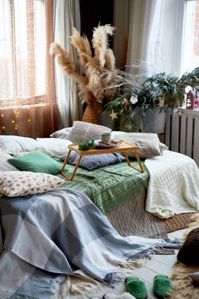 A cozy winter atmosphere in the house, The Style of Hugge. Pampas grass, lots of pillows and plaids.A tray with breakfast. — Stock Photo, Image
