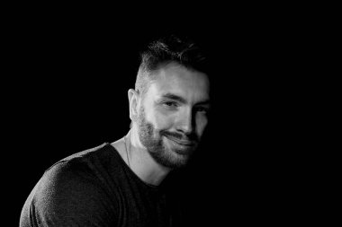 Siyah arka planda, kendinden ve hayattan memnun bir adam. Mutluluk hissi.