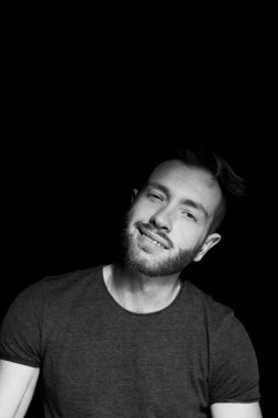 Siyah arka planda, kendinden ve hayattan memnun bir adam. Mutluluk hissi.