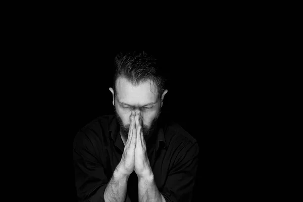 Een man met een zwarte achtergrond. Handen zijn gevouwen in de positie van het gebed.Binnenste stilte. — Stockfoto