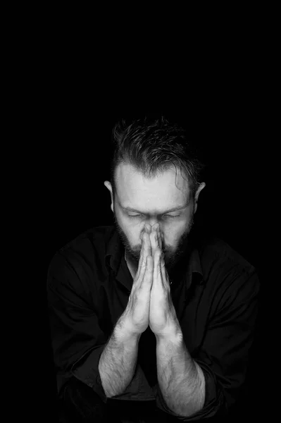 Een man met een zwarte achtergrond. Handen zijn gevouwen in de positie van het gebed.Binnenste stilte. — Stockfoto