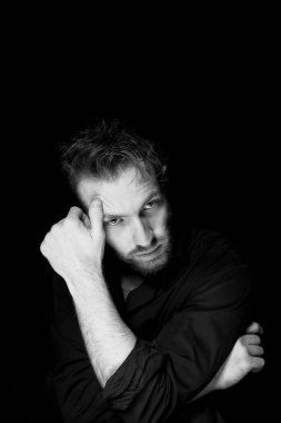 Siyah arka planda bir adam. Çerçevenin içine özenle bakıyor. Derin, anlamlı bir bakış. Yansıma hissi..