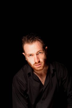 Siyah arka planda bir adam. Aggresif yüz ifadesi. Suçlu kişiliği