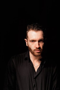 Siyah arka planda bir adam. Aggresif yüz ifadesi. Suçlu kişiliği