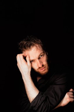 Siyah arka planda bir adam. Bakış düşünceli, soru ne yapacağımızdır. 