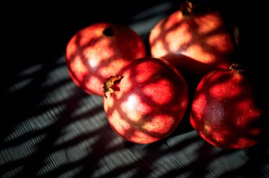 Siyah bir arka planda nar. Güneşin penceresinden yansıyan gölge. Sıcak iklimlerde vitaminler.