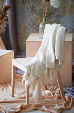 İçi ahşap sandalye, küpler ve örtülü kumaşla aydınlık. Yaratıcı bir atölye.