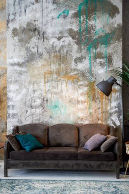 Çok renkli desenli bir duvara karşı koyu çikolata renkli bir kanepe. Siyah bir lamba. Odanın tasarımı.