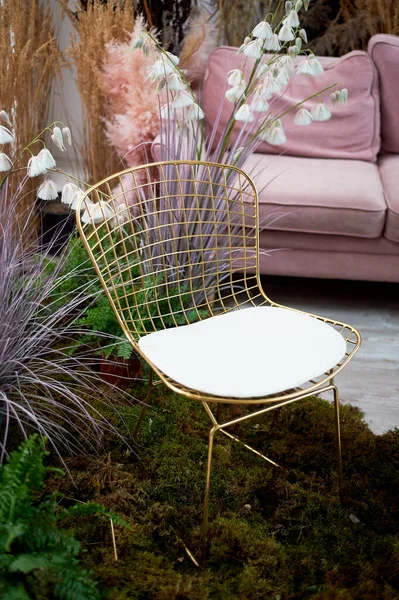 Una silla dorada con un respaldo de malla se encuentra en el musgo. Diseño ecológico.Interior elegante con cereales y flores secas. — Foto de Stock