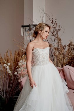 Gelin beyaz kıvrımlı bir elbise içinde dans eder ve kıvrılır. Çok güzel bir stüdyo. Avrupa tipi, sarışın..