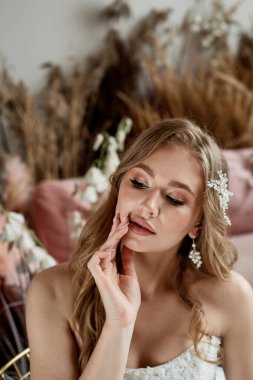 İnci küpeli güzel gelin pembe balo elbisesi giyer. Çekici esmer kadının romantik portresi. Makyajlı ve düğün saç stili pozlu..