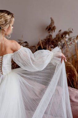 Beyaz uzun elbiseli gelin. Prensesin elbisenin kenarını nasıl tuttuğunu. Gelinin sabahı.