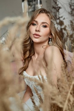 Gelinin portresi, profesyonel makyajlı. Mısır gevreği ve pampalar tarafından çerçevelenmiş. Önemli bir olay, düğün çekimi..