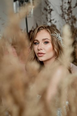 Gelinin portresi, profesyonel makyajlı. Mısır gevreği ve pampalar tarafından çerçevelenmiş. Önemli bir olay, düğün çekimi..