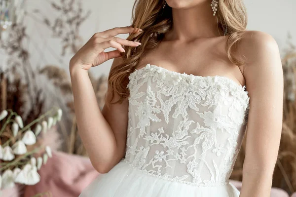 Hermosas manos de mujer con manicura francesa en un vestido de novia blanco. La mañana de la boda de una novia joven. Sin rostro. — Foto de Stock