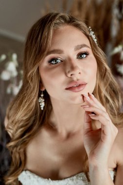 İnci küpeli güzel gelin pembe balo elbisesi giyer. Çekici esmer kadının romantik portresi. Makyajlı ve düğün saç stili pozlu..