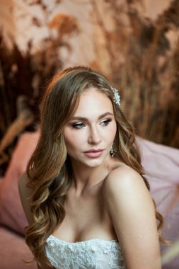 Güzel bronz tenli, profesyonel makyajlı bir gelin portresi. El yapımı saç süslemesi.