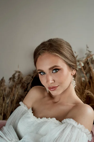 Retrato de la novia en un vestido blanco con hombros abiertos. Piel bronceada. Maquillaje profesional. — Foto de Stock