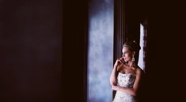 Красивая невеста с профилем, смотрящая в окно — стоковое фото