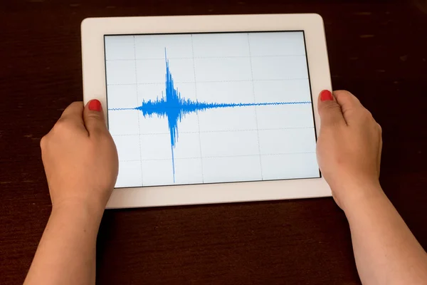 Mavi bir deprem bir tablet üzerinde gösteren bir kadın el