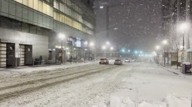 Rosslyn, Virginia 'da gece şiddetli bir kar fırtınası var. Karla kaplı caddeler arabaları gösteriyor, sokak lambaları ve modern ofis binalarıyla aydınlatılıyor. El bilgisayarı video görüntüsü.