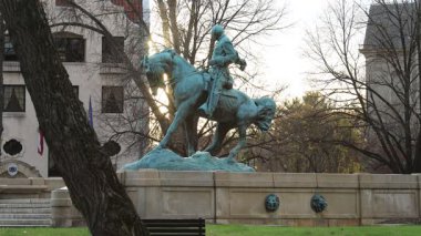 İç Savaş Generali Philip Sheridan 'ın gün batımında Gutzon Borglum tarafından yapılan binicilik heykeli. Massachusetts Bulvarı, D.C. 'deki Sheridan Circle' da sonbahar ağaçları ve geçen trafik var..