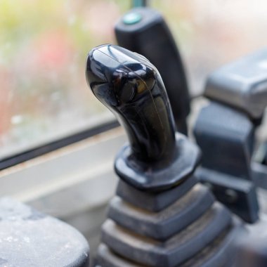 Araç taksisinde siyah bir joystick 'in yakın çekimi. Tırtıklı bir zeminde duruyor, diğer kontroller de arka planda görünüyor..