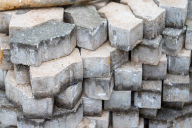 Yakın plan, birbirine kenetlenmiş beton kaldırım yığınının göz hizasında, ağırlıklı olarak gri ve bej renkli, koyu lekeli ve enkazlı..