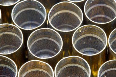 Pirinç mermi kovanlarının yakın çekim, tepeden görünüşü bir şebekeye yerleştirilmiş. Kovanlarda aşınma izleri var. İç organlarında da biraz kalıntı var..