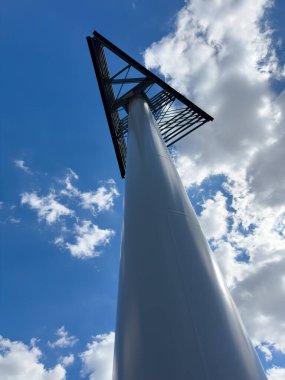 Modern metal mimarisi beyaz bulutlarla dolu açık mavi gökyüzüne doğru yükseliyor.