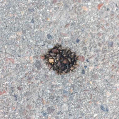 Küçük taşlı asfalt ve ortasında koyu yağ lekesi.