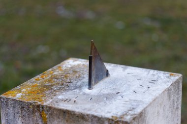 Yıpranmış taş güneş saati cüceleriyle zamanı gösteriyor.