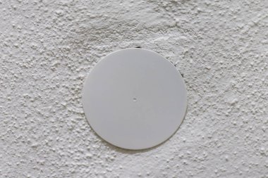 Yuvarlak beyaz kaplama beyaz bir duvardaki elektrik kutusunu kaplıyor.