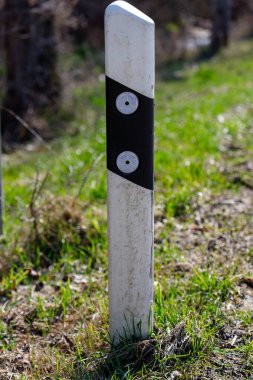 Yol kenarı çizici direği ve gündüz boyunca yeşil çimlerin üzerinde yansıtıcılar