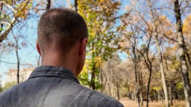Boşandıktan sonra bir sonbahar parkında tek başına yürüyen bir adamın arkası. Yüksek kalite 4k görüntü