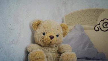 Bej çocuk yatağında oturan peluş ayı. Sıcak çocuk odası. Yüksek kalite 4k görüntü