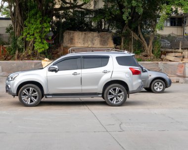 Açık otoparka park eden sol tarafı manzaralı şık gümüş renkli bir SUV spor araba şehir caddesinde..