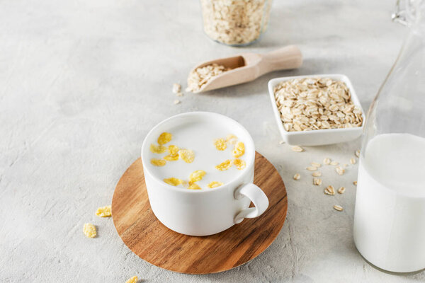 Чашка домашнего немолочного альтернативного молока из овсяных хлопьев. Веганское овсяное молоко на сером бетонном столе.