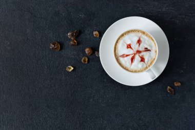 Kahve fincanı, siyah arka planda sanat ve şeker parçaları. Latte sanatı. 