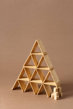 Esmer şeker parçalarıyla üçgen şeklinde dengelenmiş kare kurabiyeli yaratıcı kompozisyon hayatı.