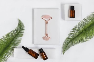 Pembe kuarklar, beyaz arka plan manzaralı kozmetik masaj yağıyla yüz masajı yapar. Yüz bakımı tedavisi.